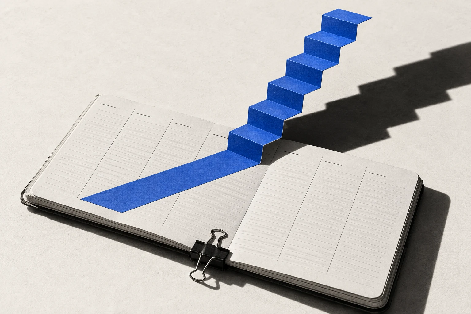 A cobalt paper staircase rises from the pages of a weekly planner.